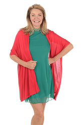 Woman wearing a green dress with a red cardigan on a white background.