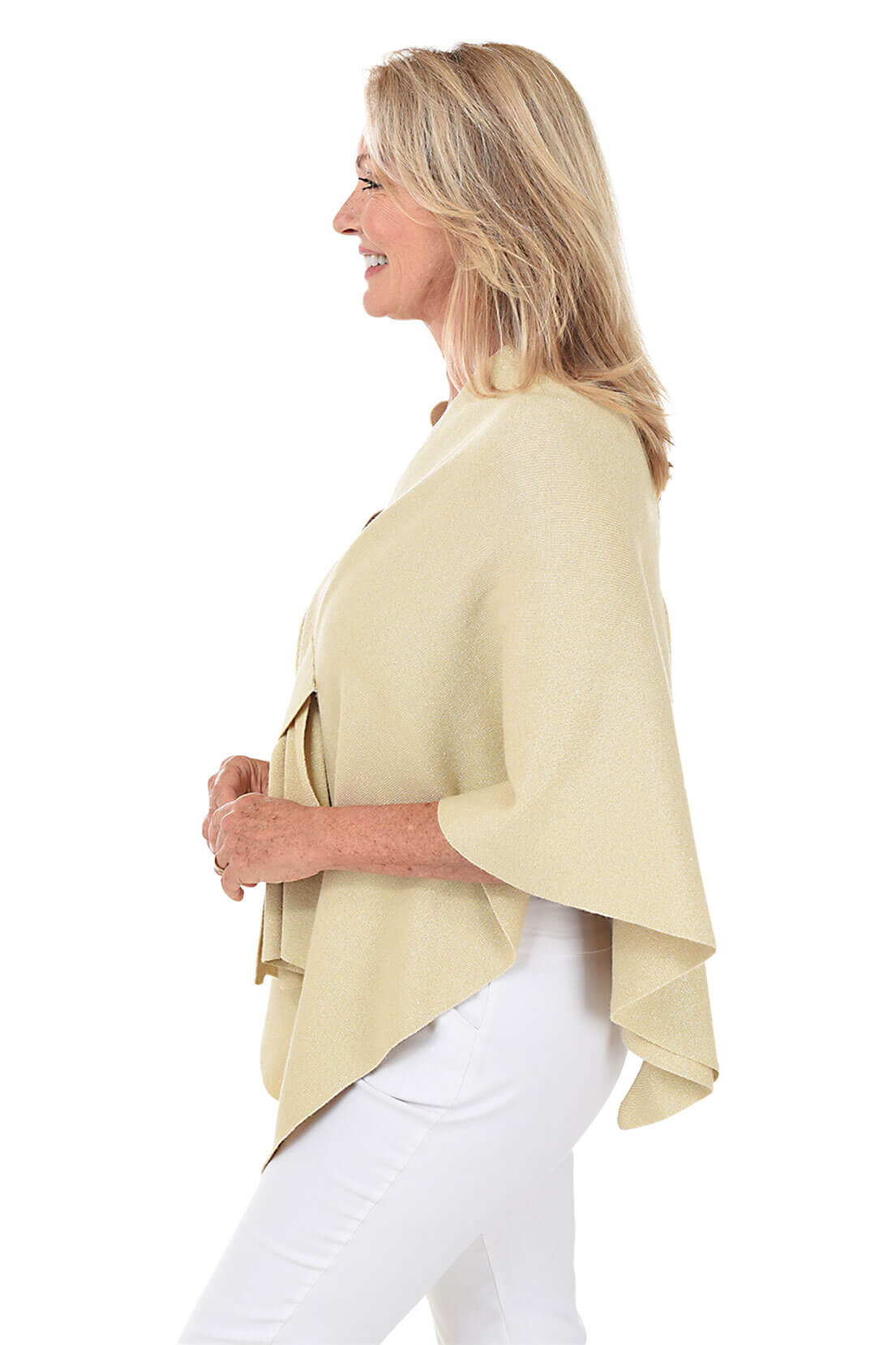 A woman wears a glittery gold wrapped shawl with a white pant against a white background. Side shot.