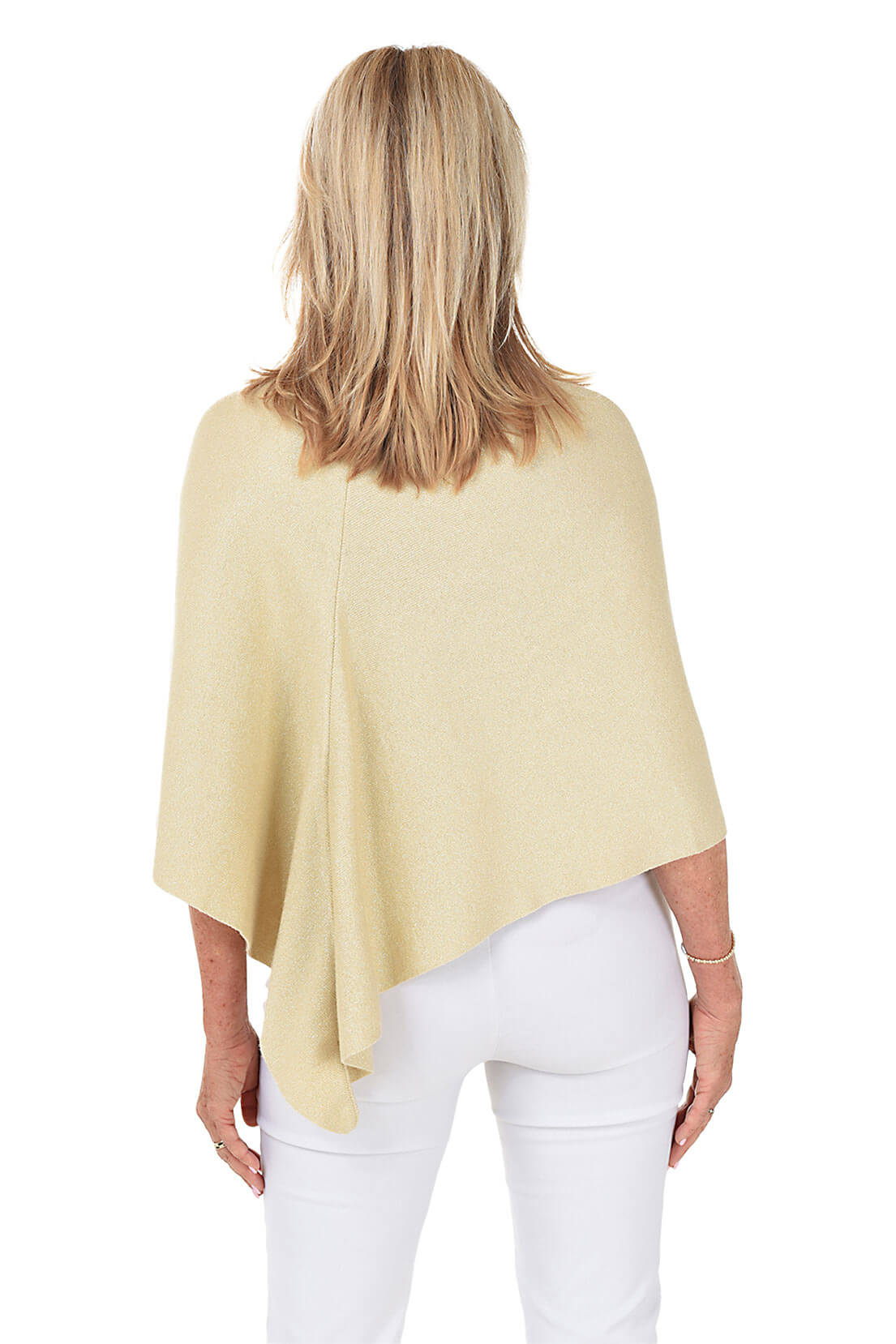 A woman wears a glittery gold wrapped shawl with a white pant against a white background. Back shot.