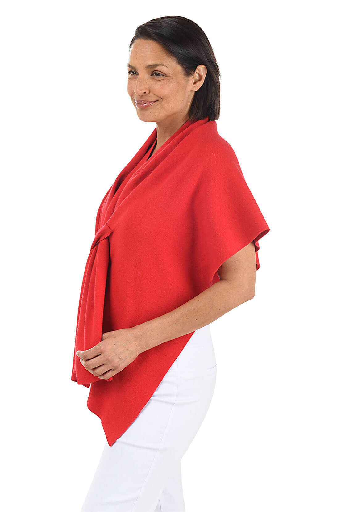 A woman wears a red wrapped shawl over a white top and pants against a white background. Side shot.
