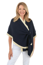 Woman wearing a navy blue wrap with beige trim on a white background.