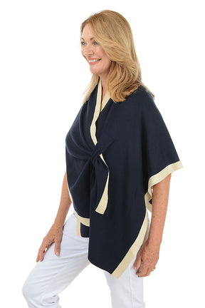 Woman wearing a navy blue wrap with beige trim on a white background. Side shot.