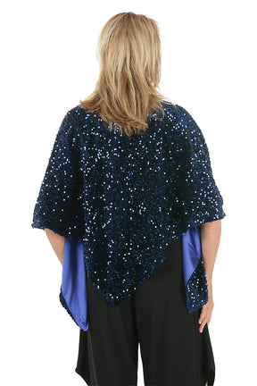 Woman wearing a black dress with a blue sequin shawl on a white background. Back shot.