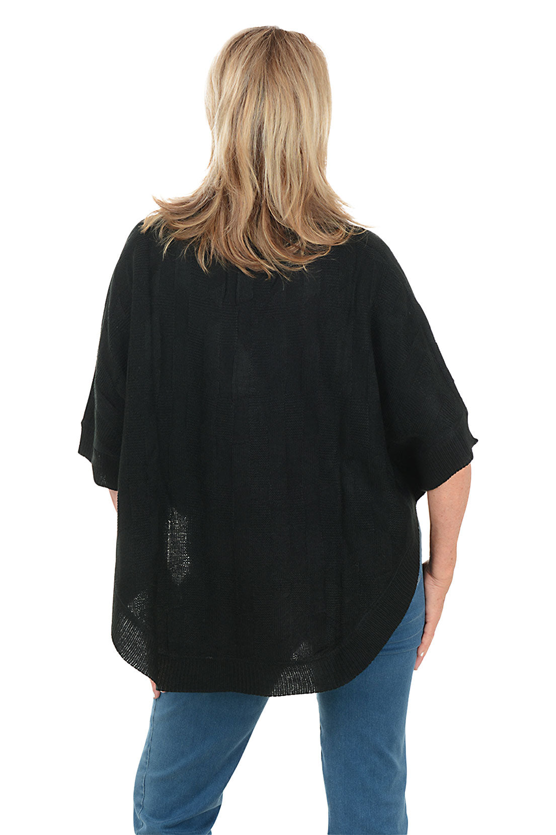 Woman wearing a black poncho and blue jeans on a white background. Back shot.