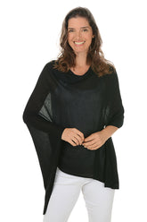 A woman wearing a black bamboo poncho with an asymmetrical hemline, paired with white pants.