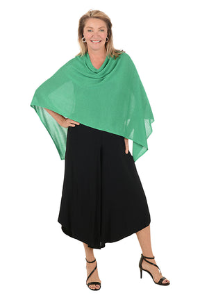 Woman wearing a green poncho and black pants on a white background