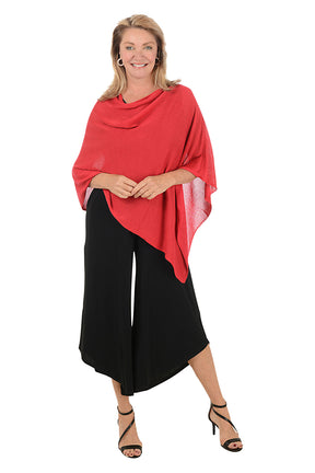 Woman wearing a red poncho over a black outfit on a white background