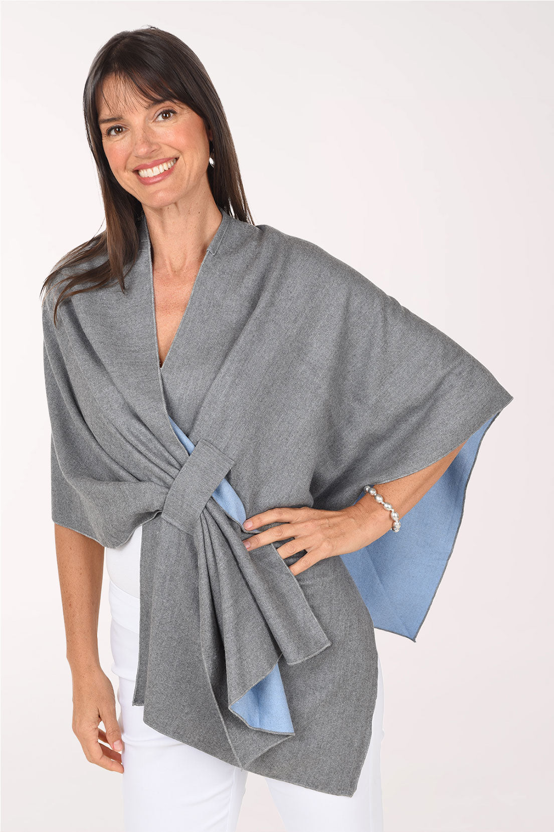 Front view of the grey Kate wrap with one hand on the hip, showing the pulled-through keyhole closure and the sky-blue lining at the open edge.