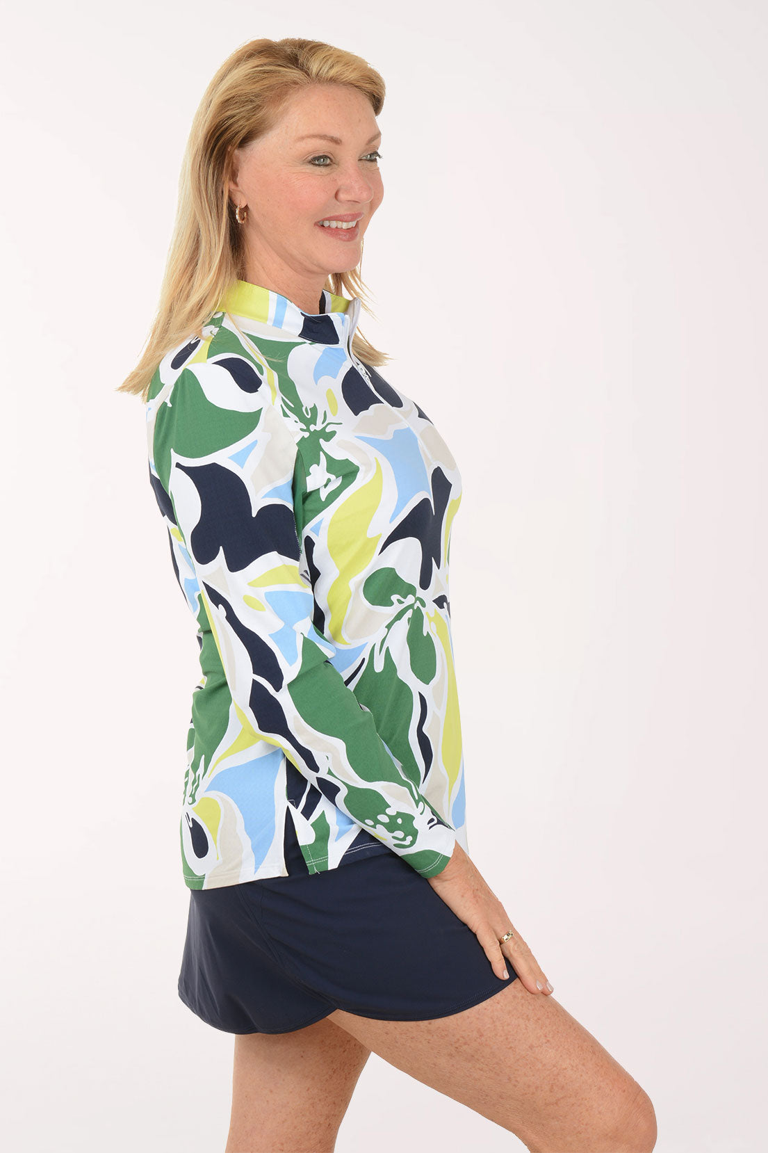 Woman wearing a colorful patterned top and navy skirt on a white background