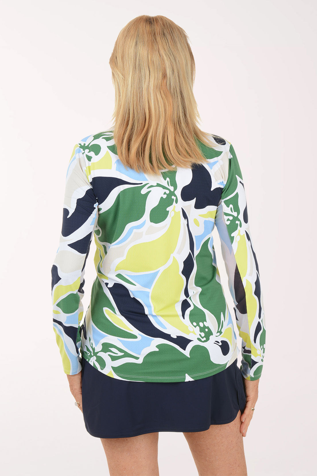 Woman wearing a colorful patterned top and navy skirt on a white background