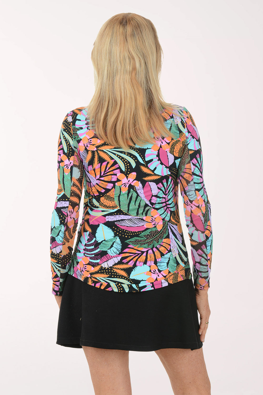 Person wearing a colorful floral patterned top with a plain background