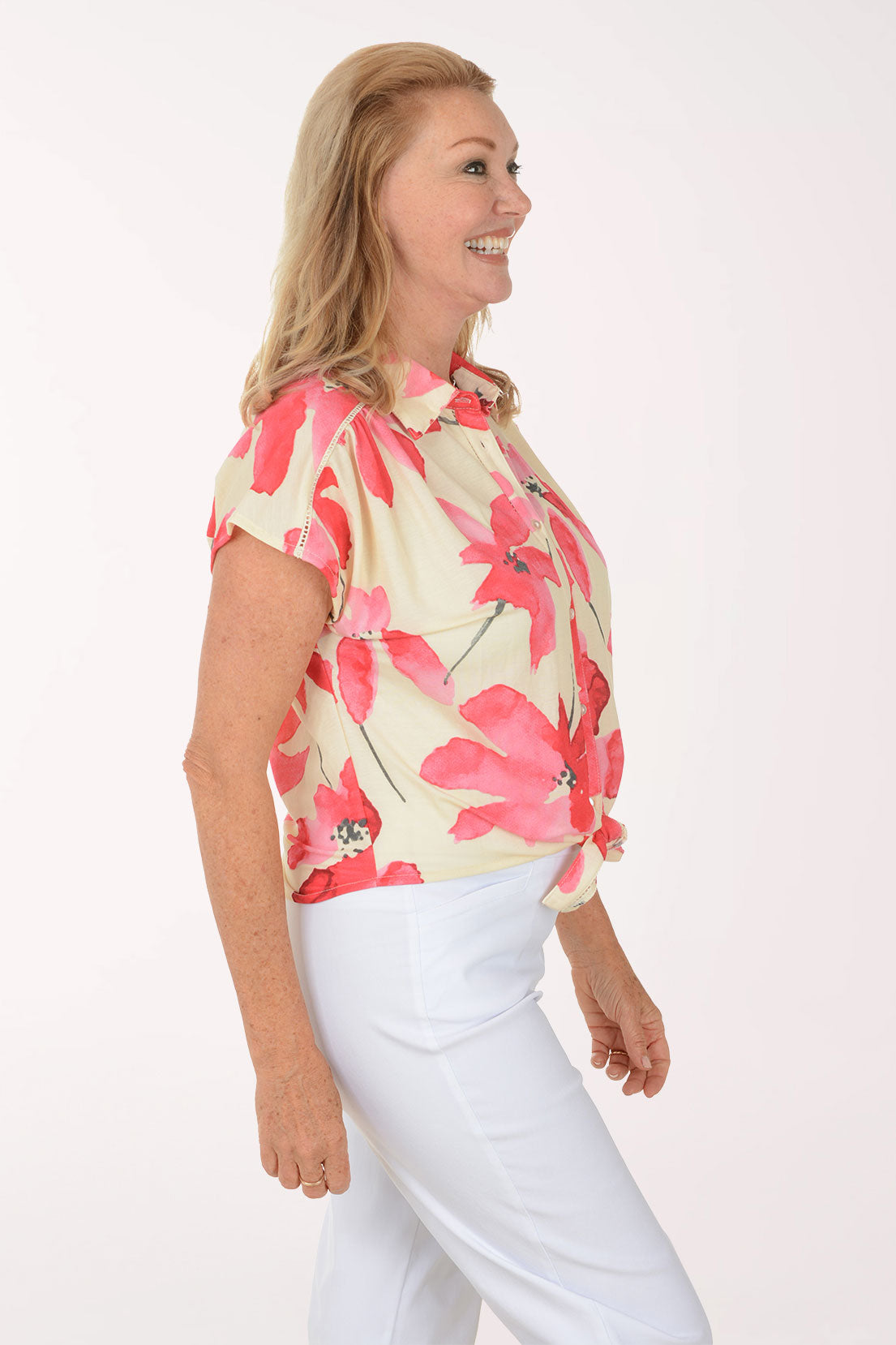 Woman wearing a floral blouse and white pants on a white background