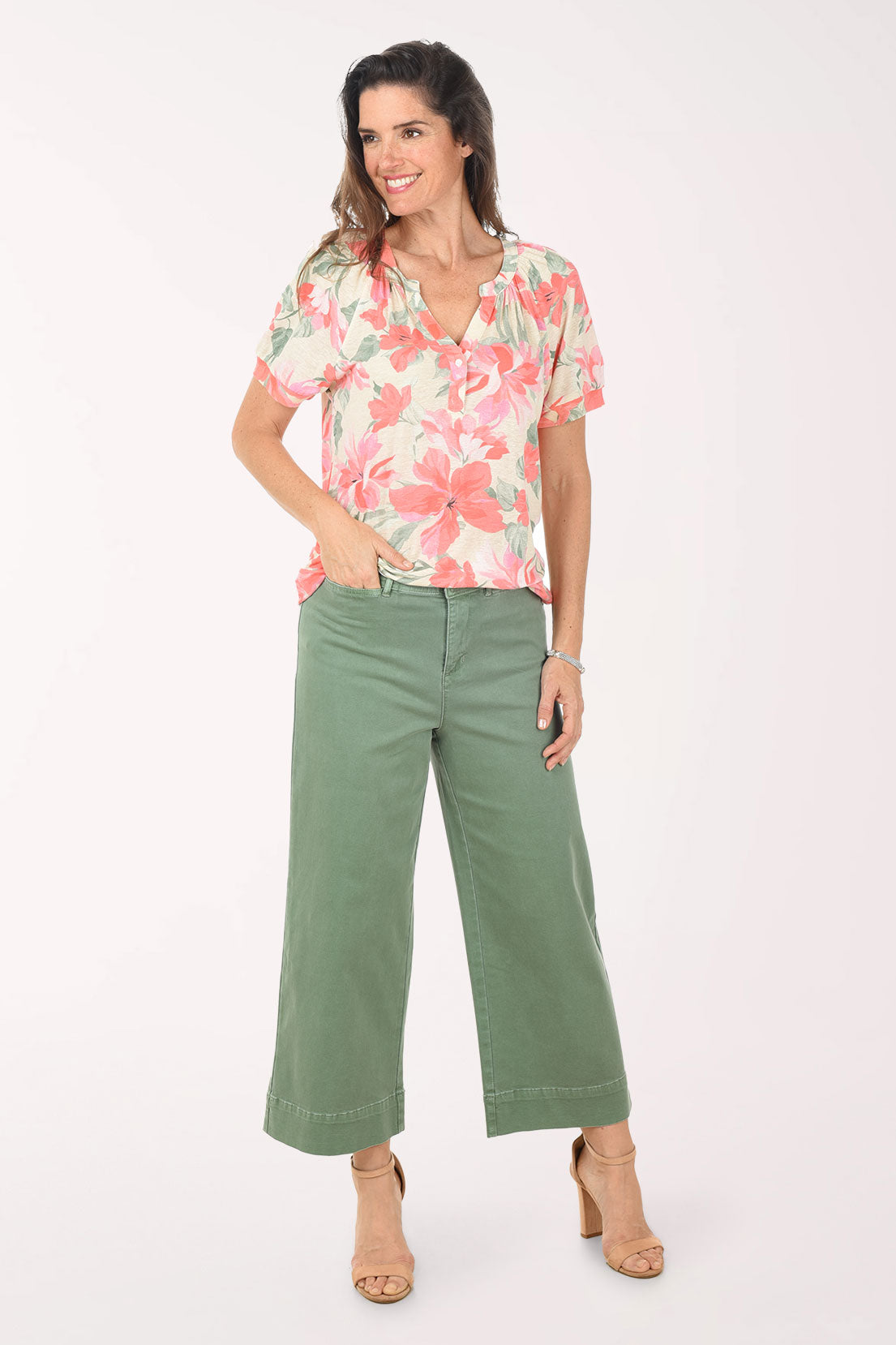 Woman wearing a floral blouse and green pants on a white background