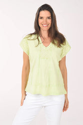 Woman wearing a light green blouse and white pants on a white background