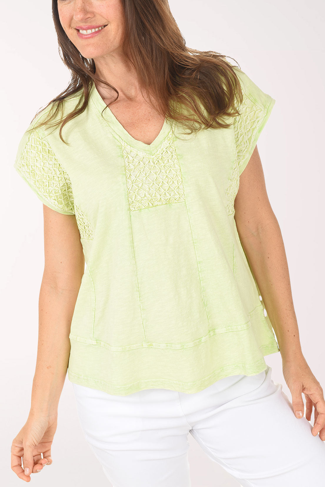 Woman wearing a light green blouse and white pants on a white background