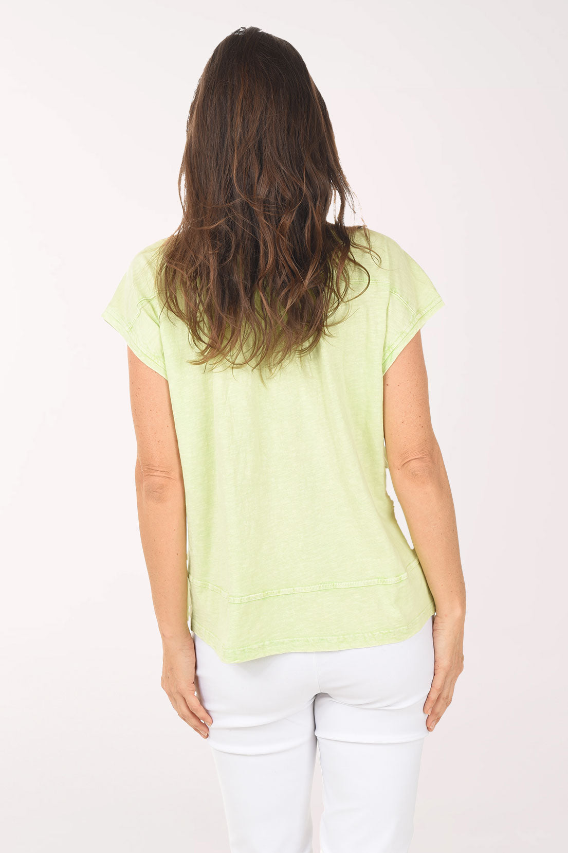 Woman wearing a light green blouse and white pants on a white background