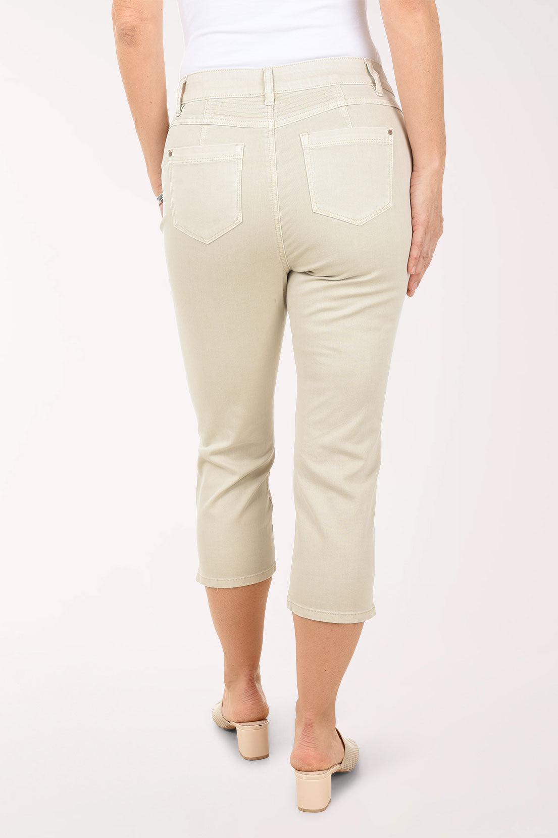 Person wearing beige capri pants on a white background