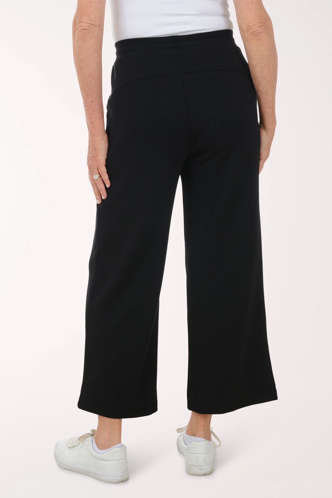 Person wearing black wide-leg pants on a white background