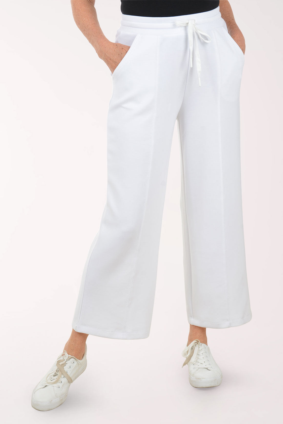 Person wearing white wide-leg pants on a white background