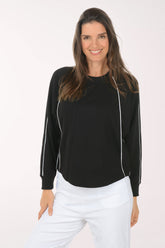 Woman wearing a black long-sleeve top with white trim on a white background