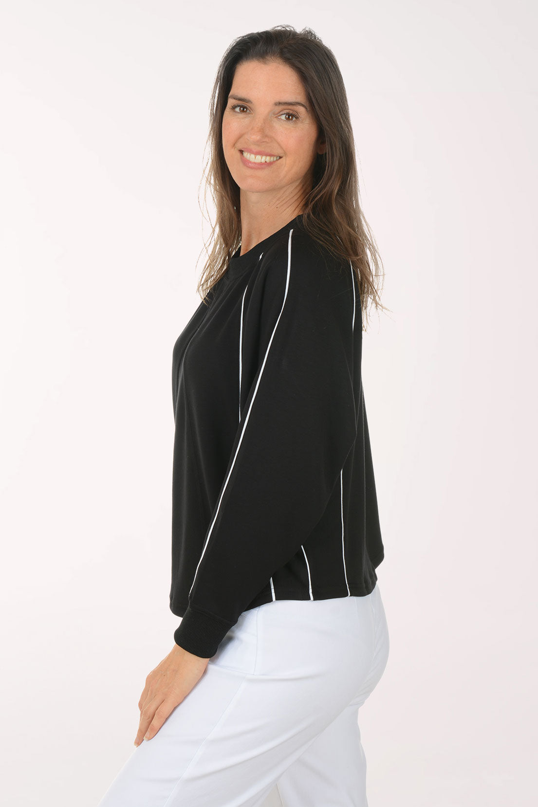 Woman wearing a black long-sleeve top with white trim on a white background
