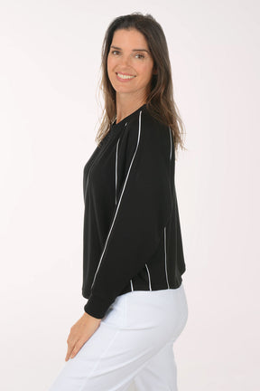 Woman wearing a black long-sleeve top with white trim on a white background