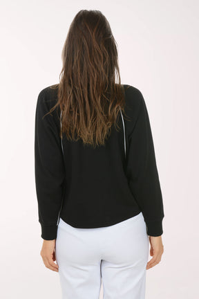 Woman wearing a black long-sleeve top with white trim on a white background