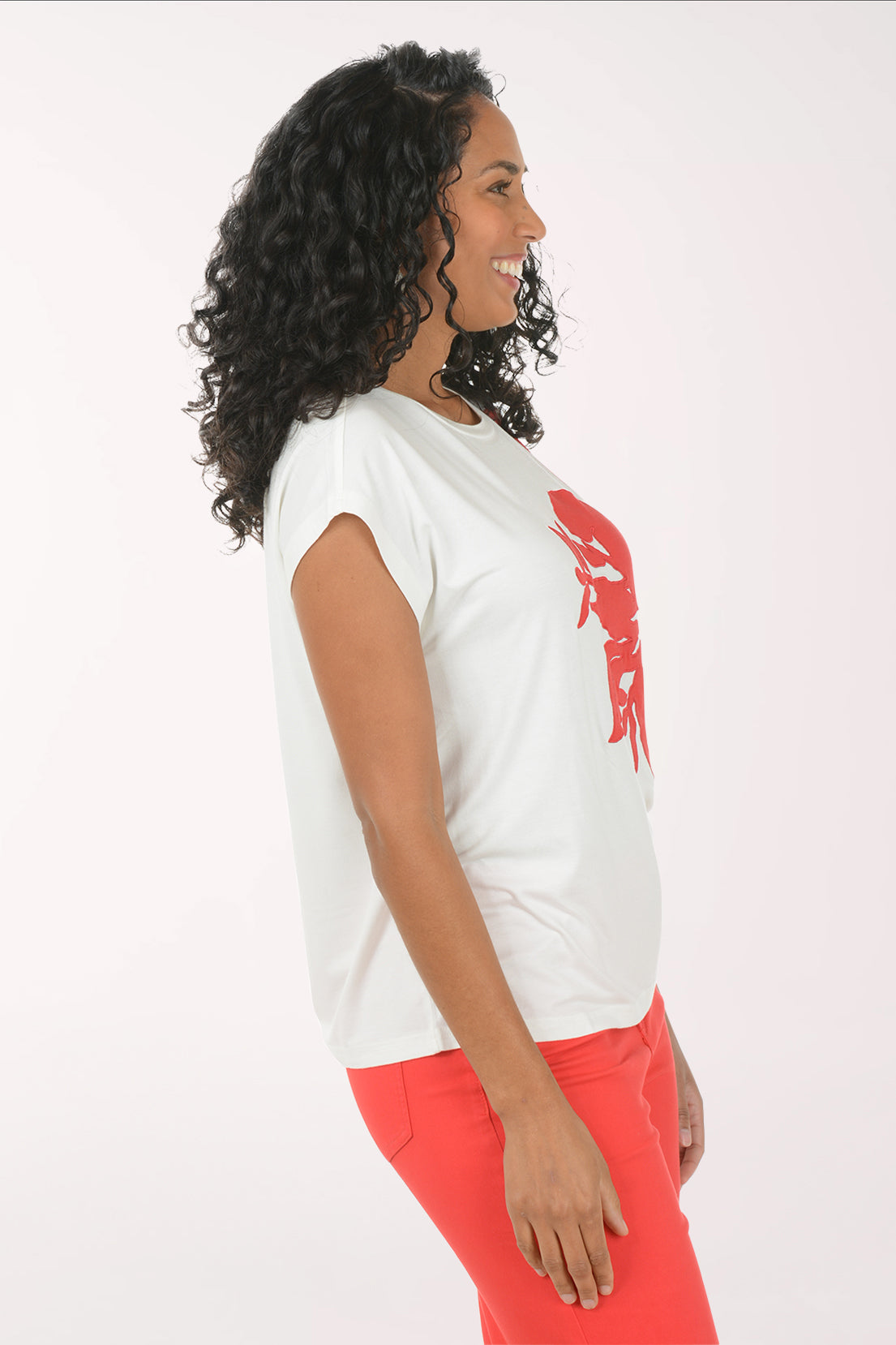 Woman wearing a white t-shirt with a red floral design and red pants on a white background