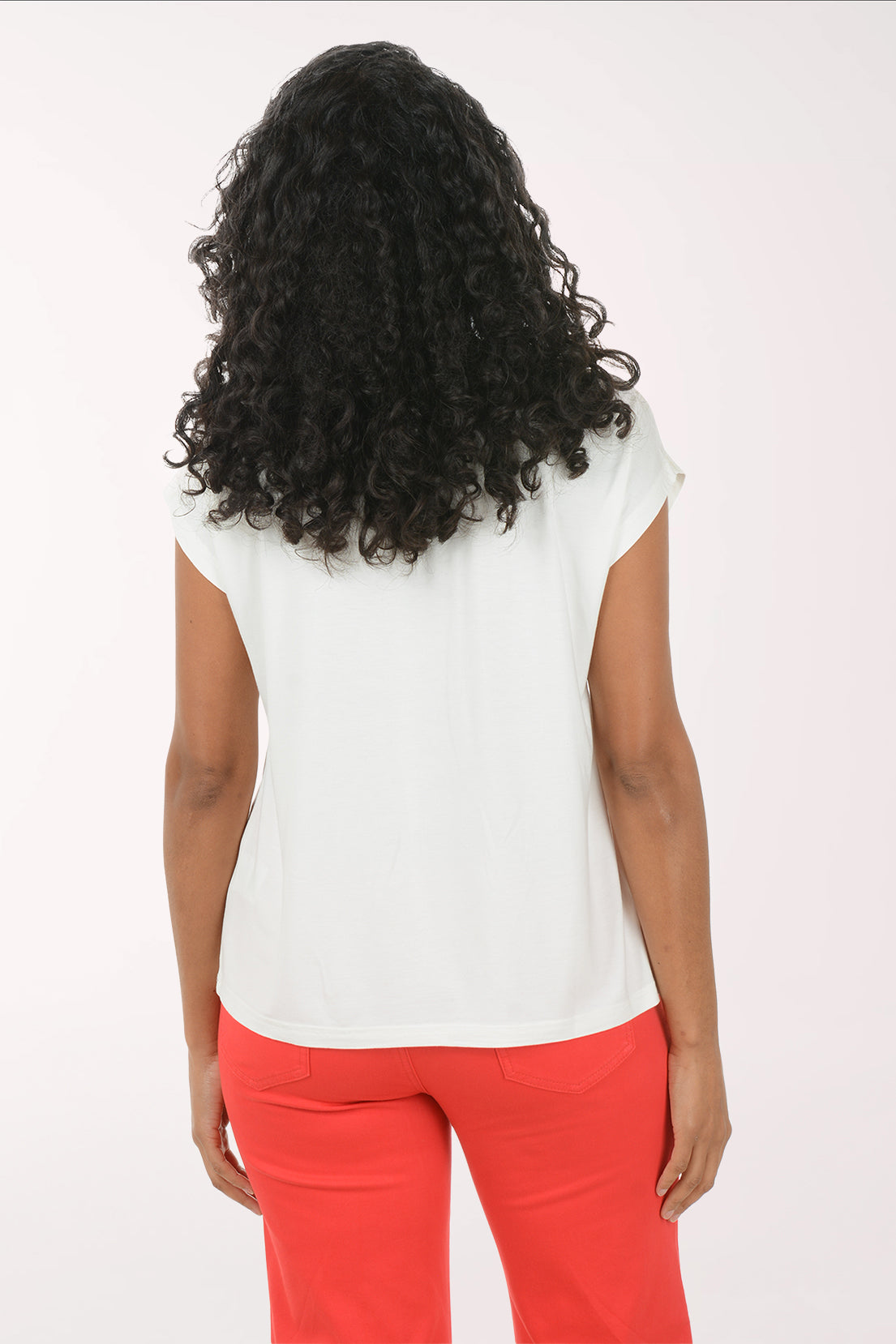 Woman wearing a white t-shirt with a red floral design and red pants on a white background