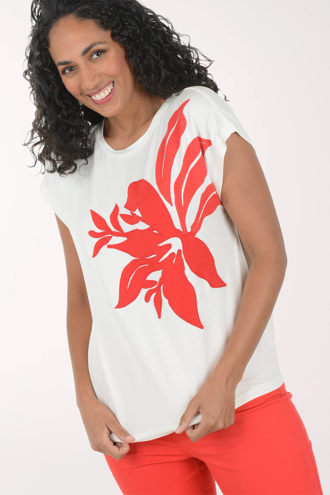 Woman wearing a white t-shirt with a red floral design and red pants on a white background