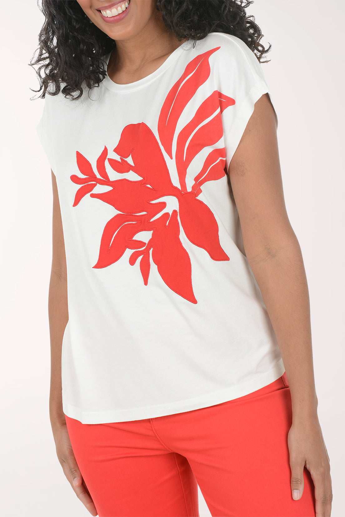 Woman wearing a white t-shirt with a red floral design and red pants on a white background