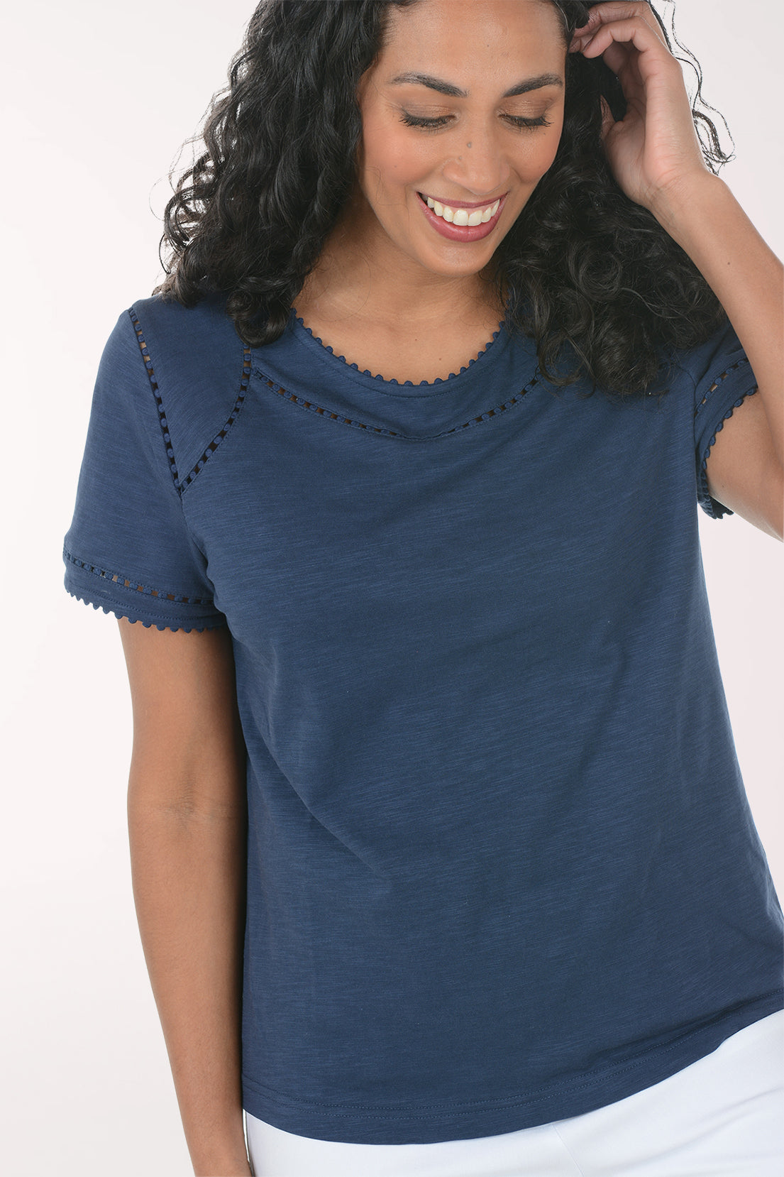 Woman wearing a blue top and white pants on a white background