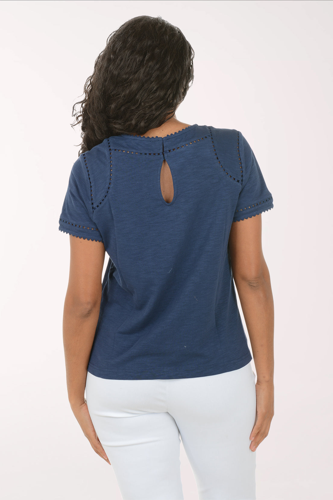 Woman wearing a blue top and white pants on a white background