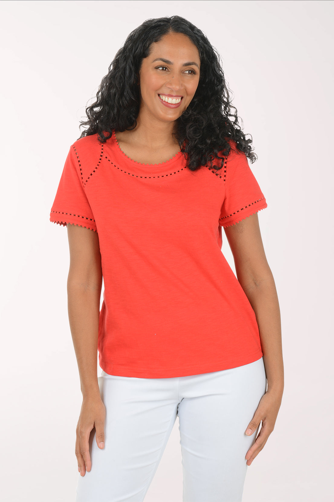 Woman wearing a red top with white pants on a white background