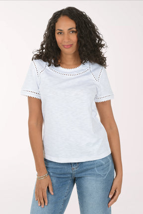 Woman wearing a light blue top with lace details and jeans on a white background