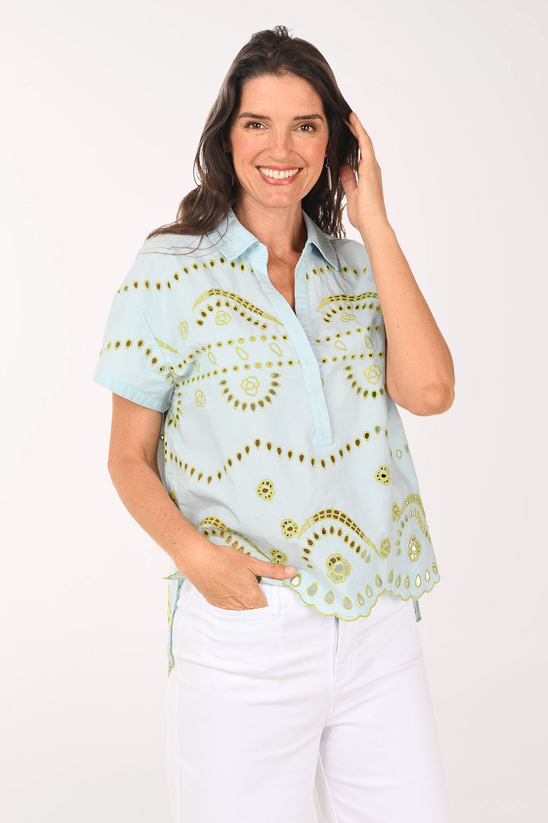 Woman wearing a light blue blouse with gold patterns on a white background