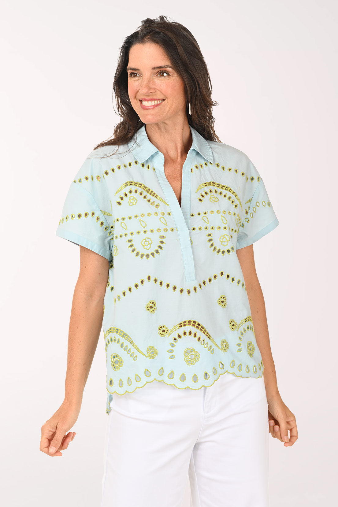 Woman wearing a light blue blouse with gold patterns on a white background