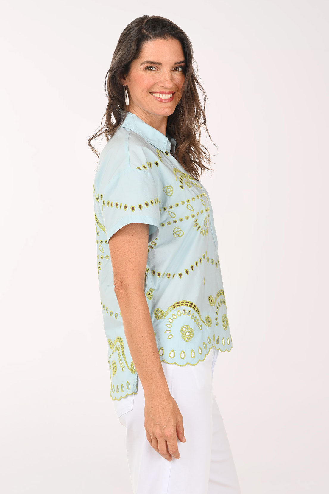 Woman wearing a light blue blouse with gold patterns on a white background