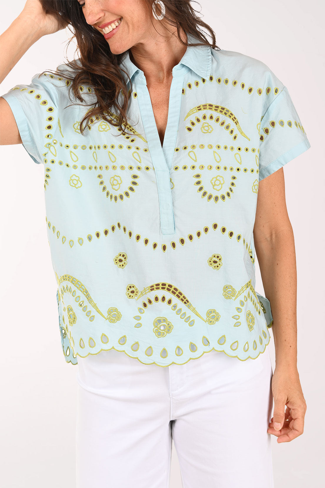 Woman wearing a light blue blouse with gold patterns on a white background