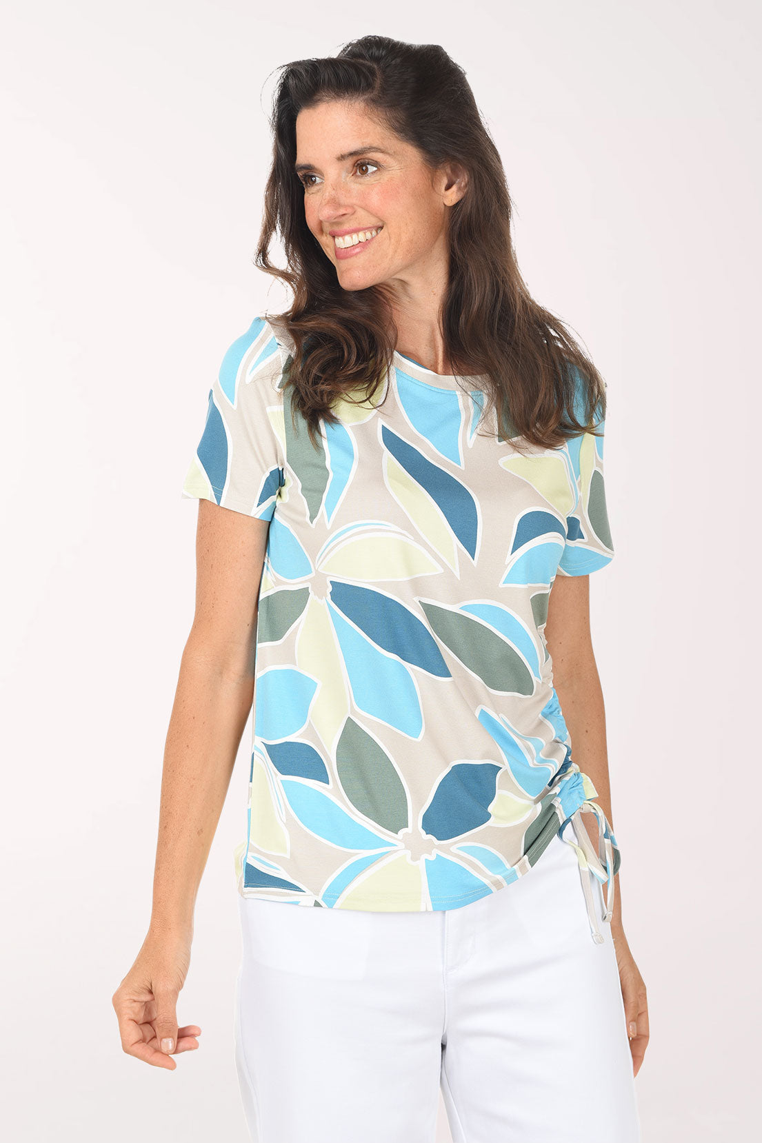 Woman wearing a colorful leaf-patterned top against a white background