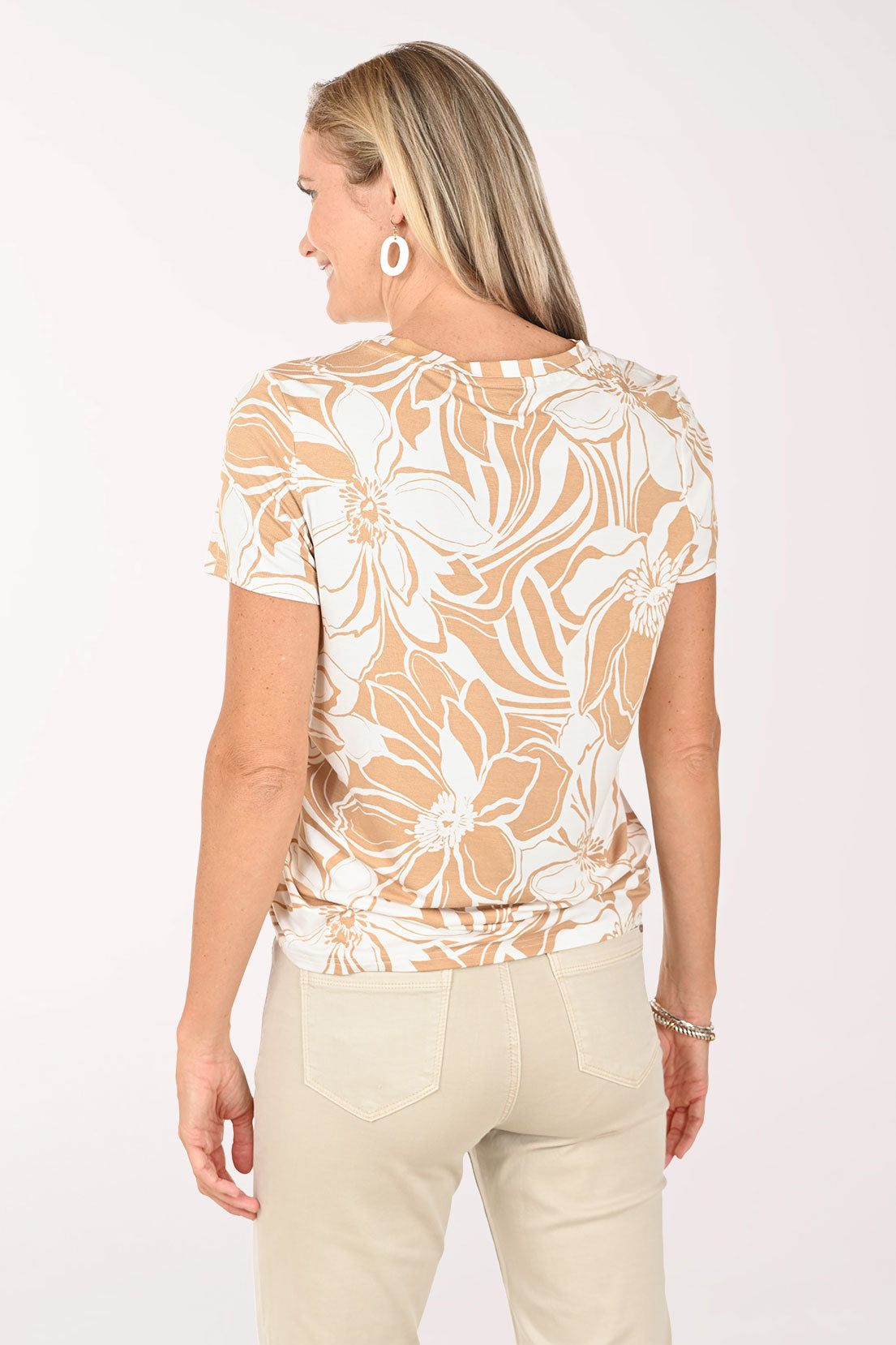 Woman wearing a floral blouse and beige pants on a white background