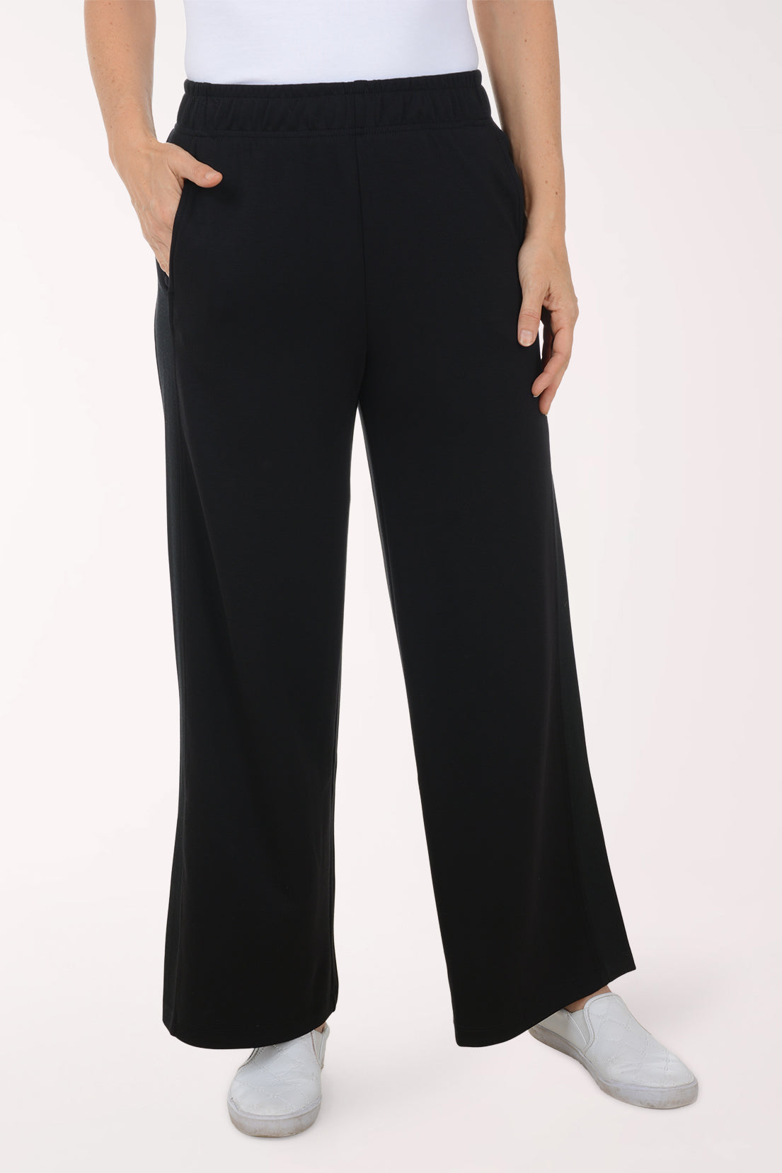 Person wearing black wide-leg pants and white shoes on a white background