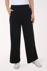 Person wearing black wide-leg pants and white shoes on a white background