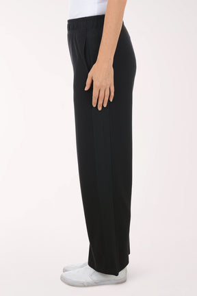 Person wearing black wide-leg pants and white shoes on a white background