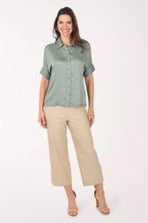 Woman wearing a green shirt and beige pants on a white background