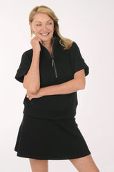 Woman wearing a black short sleeve top and skirt on a white background