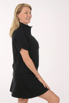 Woman wearing a black short sleeve top and skirt on a white background
