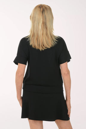 Woman wearing a black short sleeve top and skirt on a white background