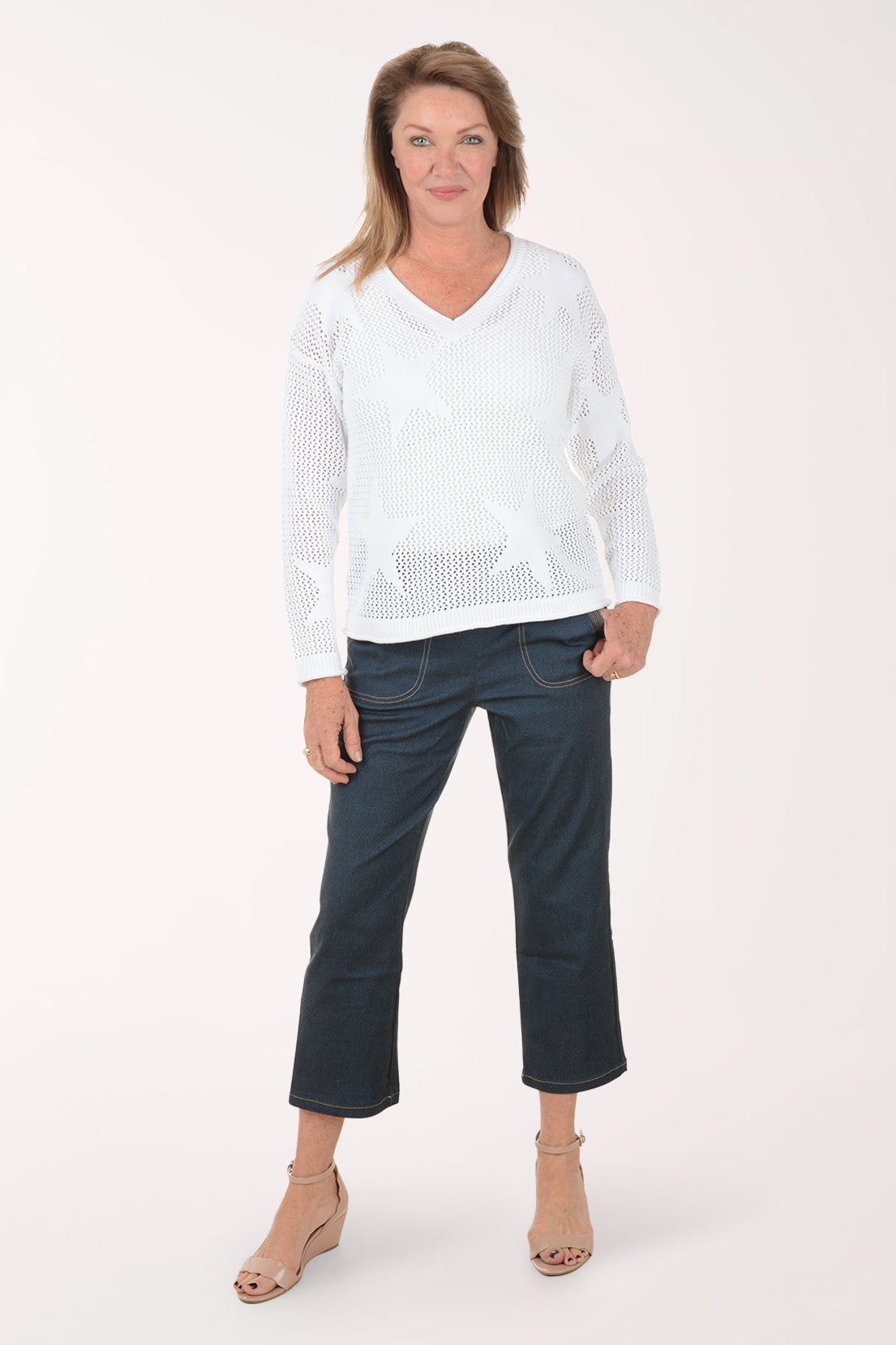 Woman wearing a white sweater and dark blue jeans on a white background
