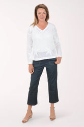 Woman wearing a white sweater and dark blue jeans on a white background